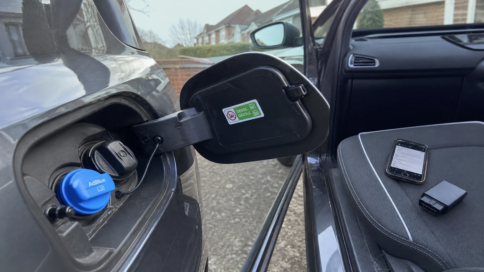 UK diesel driver checking an AdBlue warning with a phone OBD scanner before booking a garage